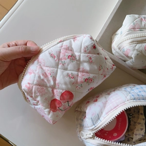 Détail de la trousse de maquillage matelassée à fleurs avec fermeture éclair beige