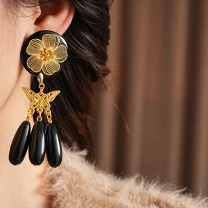Detail of vintage beaded flower butterfly earrings with black teardrop tassels on model