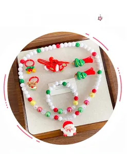 Flat lay of a Christmas jewelry set for kids with Santa pendant, bracelets, and hair clips