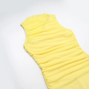 Détail d'une robe en résille jaune vif avec texture plissée complexe et design froncé