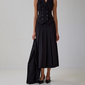 Détail d'un ensemble élégant deux pièces avec gilet croisé et jupe longue plissée noire