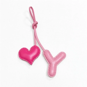 Detailed view of handmade leather heart and letter Y bag charm with fuchsia stitching