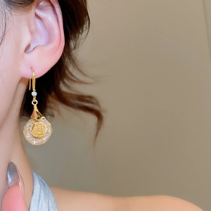 Detailed close-up of a gold floral earrings with crystal accents on a model's ear