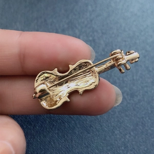 Detailed view of the golden violin brooch back featuring a secure metal safety pin clasp