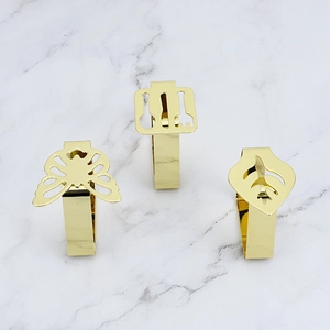 Detailed view of three gold leaf and cutlery shaped stainless steel tablecloth clips