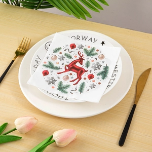 Close-up of Christmas paper napkins with reindeer and pine patterns on dinner plates