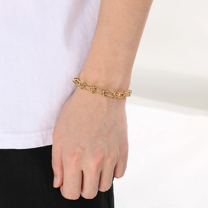Detail of a gold plated titanium steel knotted chain bracelet worn on a model's wrist