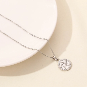 Dettaglio della collana con ciondolo sole e stella in argento su un piatto di ceramica