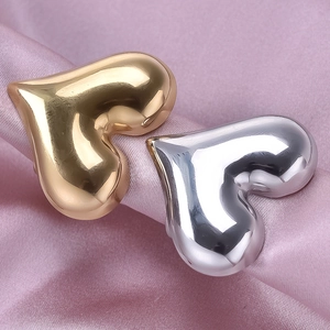 Irregular 18K gold and silver heart-shaped stainless steel rings on pink silk background