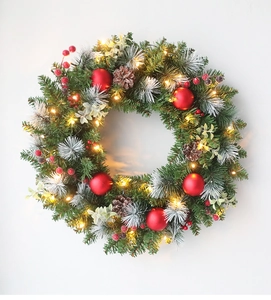 Detail of Christmas wreath with red berries, pine cones and warm glowing LED lights