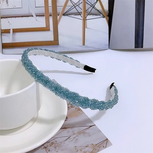 Blue beaded braided headband with white fabric lining on a styled white background