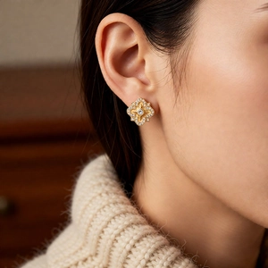 Detailed close-up of vintage gold floral earrings with zircon stones on model ear