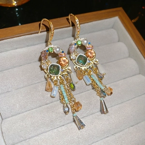 Close-up of bohemian gold tassel earrings with colorful gemstones and crystal drops