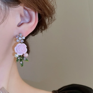 Detailed view of floral earring with pink rose, crystal accents, and pearl on model