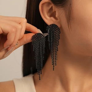 Close-up of black geometric tassel earrings with rhinestones on a model's ear
