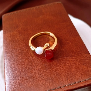 Detailansicht eines vergoldeten Rings mit weißer Süßwasserperle und roter Karneol-Perle