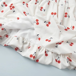 Detailed view of red cherry print on white crepe fabric with soft inner lining