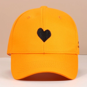 Detailed view of bright orange baseball cap with black 3D heart embroidery on the front