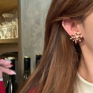 Close-up of a festive red zircon pearl earring featuring a starburst firework design