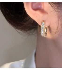 Close-up of elegant gold hoop earrings with zircon pavé set on model for a retro look