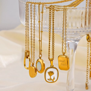 Close-up of 18K gold plated square and rose pendants hanging on glass display