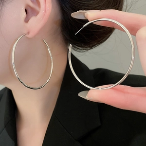 Close-up of large silver circular hoop earrings shown in hand for scale and size comparison