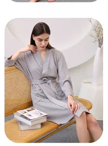 Detail of light gray waffle robe with white piping and waist tie on wooden bench