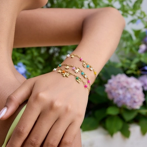 Detailed view of layered 18K gold-plated bracelets with colorful beads and floral charms