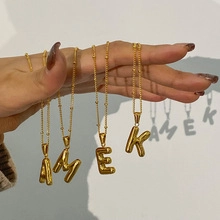 Creative hand-held shot of gold balloon-style letter charms casting sharp shadows on wall
