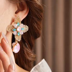 Close-up of vintage floral drop earring with pink and blue crystals on golden metal base