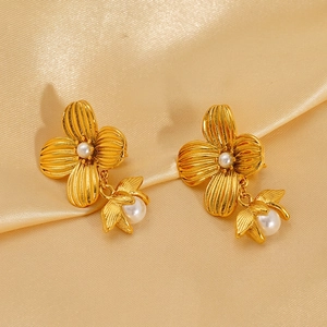 Elegant gold flower pearl earrings in stainless steel on a luxury satin background
