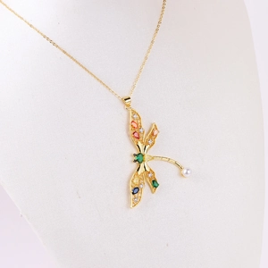 Golden dragonfly necklace with colorful zircon crystals and pearl on a white mannequin