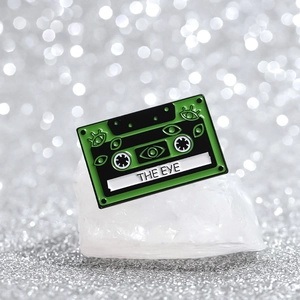 Green retro cassette enamel pin featuring 'THE EYE' illustration and pop art style music badge