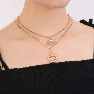 Collana a doppio strato in oro con ciondoli a cuore e diamante su collo di modella
