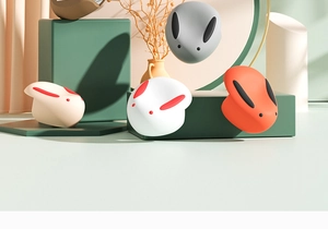 Dettaglio dei paraspigoli in silicone a forma di coniglio in bianco, arancione e grigio