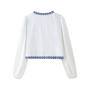 Back view of white long-sleeve crop top with blue ethnic embroidery and fine texture