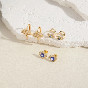Evil eye geometric zircon earrings set in gold finish with blue stones on white texture