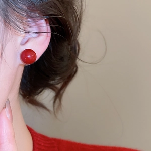 Close-up of elegant red pearl stud earrings on model with a polished glossy finish