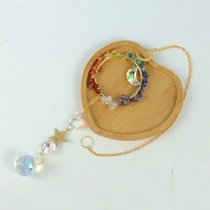 Golden suncatcher with moon crystal and colorful gemstones on a wooden tray