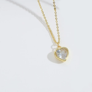 Close-up of golden necklace with a heart-shaped clear zircon pendant in natural light