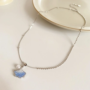 Detailed view of silver ginkgo leaf necklace with blue zircon and elegant pearl detail
