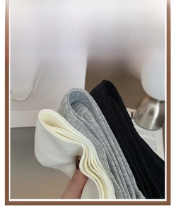Detailed knit texture of off-white, gray, and black crew socks in cotton blend