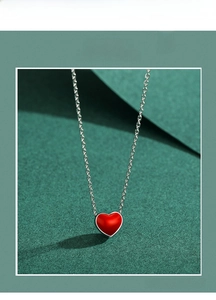 Close-up of a vibrant red heart-shaped enamel pendant on a silver-tone chain necklace