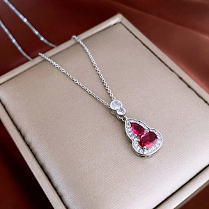 Macro shot of silver gourd pendant with red zircon gems in a gold jewelry box