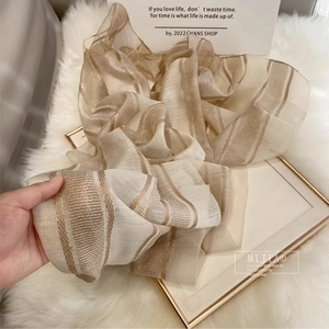 Detail of silk wool scarf with gold stripes on white plush surface and gold frame