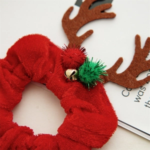 Close-up of velvet Christmas scrunchie with golden bell and glittery pom-pom ornaments