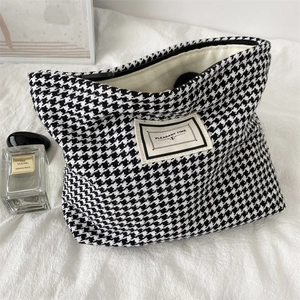 Detail of houndstooth cosmetic bag fabric with woven texture and a fabric brand label