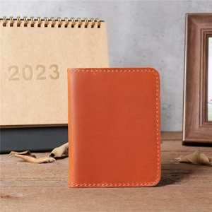 Close-up of vintage brown leather card holder with hand-stitched edges on wooden table