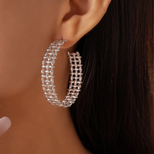 Close-up of model wearing silver hollow grid hoop earrings with textured metal finish