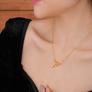 Detail view of a gold-plated snake pendant necklace with a clear zircon gem on a model